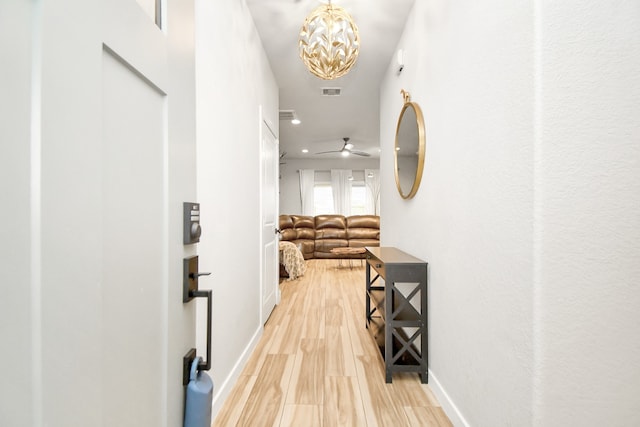 corridor with hardwood / wood-style floors and a notable chandelier