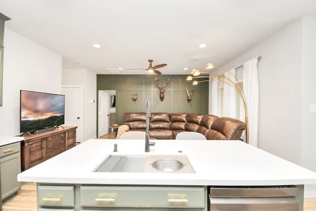 kitchen with sink, an island with sink, green cabinetry, and light hardwood / wood-style flooring