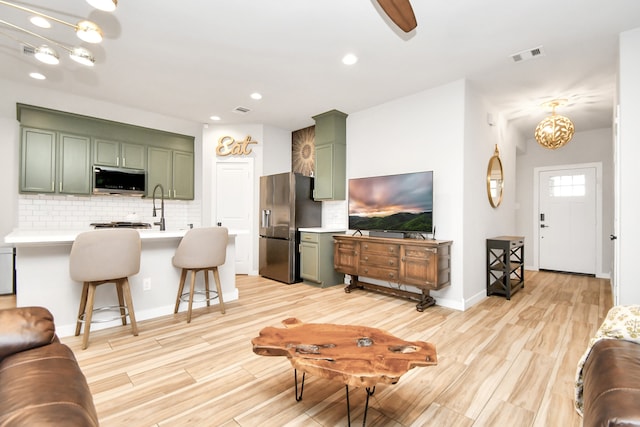 living room with light wood-type flooring, sink, and ceiling fan