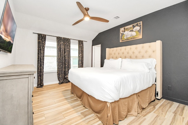 bedroom with ceiling fan, light wood-type flooring, and vaulted ceiling