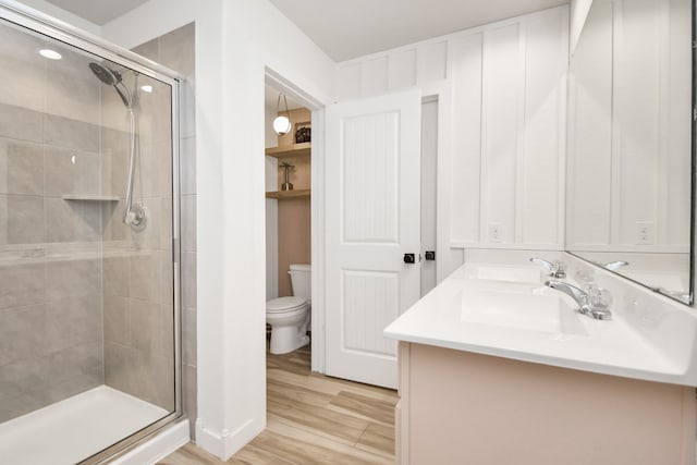 bathroom with vanity, wood-type flooring, toilet, and a shower with door