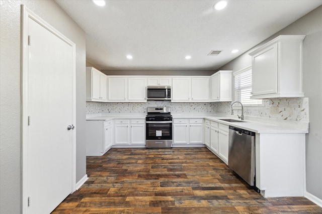 kitchen featuring appliances with stainless steel finishes, sink, backsplash, white cabinets, and dark hardwood / wood-style floors