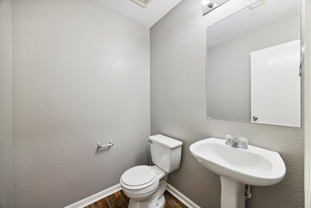 bathroom with toilet, a textured ceiling, sink, and hardwood / wood-style floors