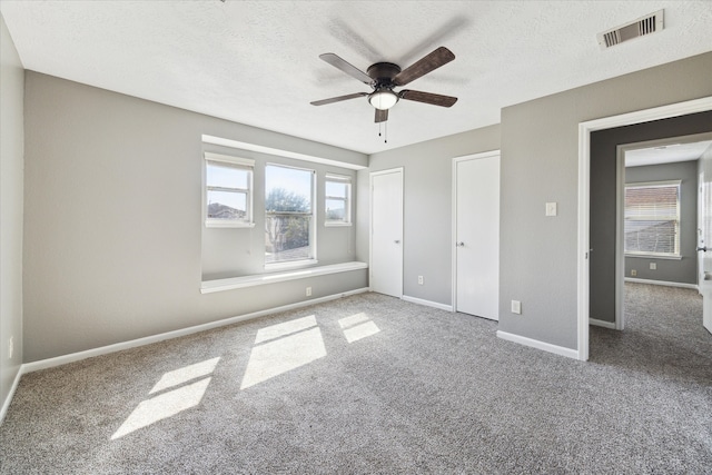 unfurnished bedroom with ceiling fan, carpet flooring, and a textured ceiling