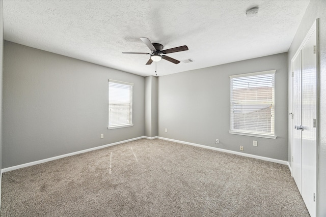 unfurnished room with ceiling fan, a textured ceiling, carpet floors, and plenty of natural light