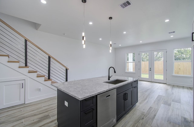 kitchen with a center island with sink, stainless steel dishwasher, light hardwood / wood-style flooring, pendant lighting, and sink