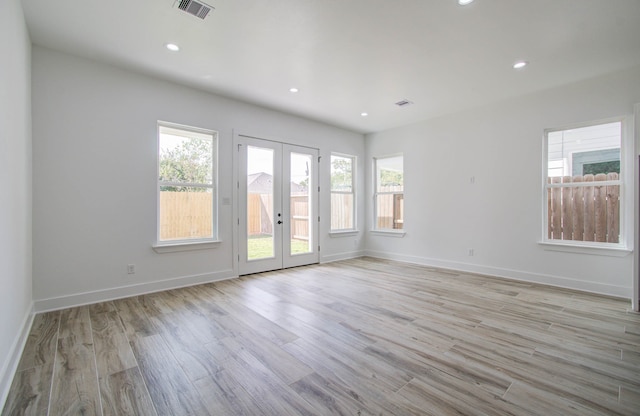 empty room featuring french doors and light hardwood / wood-style flooring