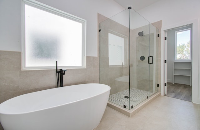 bathroom with tile patterned flooring, tile walls, and shower with separate bathtub