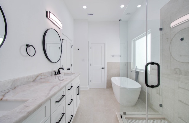 bathroom featuring vanity, independent shower and bath, and tile walls