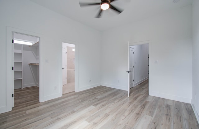 unfurnished bedroom featuring a spacious closet, ceiling fan, ensuite bathroom, and light hardwood / wood-style floors