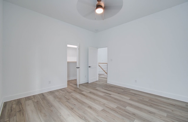 unfurnished bedroom with a spacious closet, light hardwood / wood-style flooring, a closet, and ceiling fan