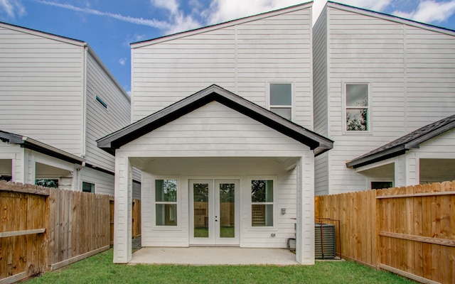 rear view of house with french doors, a patio, and a lawn