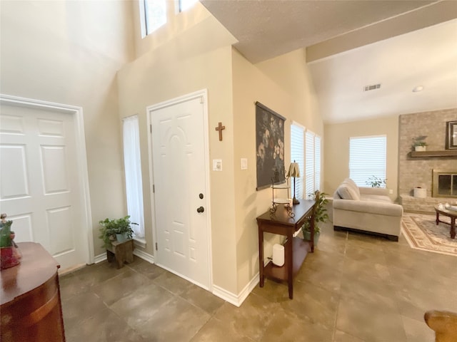 entryway featuring a large fireplace, a towering ceiling, and a wealth of natural light