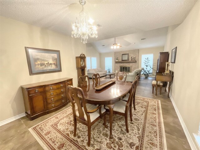 dining room featuring vaulted ceiling, a brick fireplace, a textured ceiling, and ceiling fan with notable chandelier