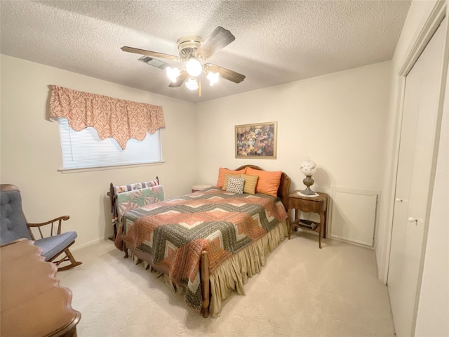 carpeted bedroom featuring a textured ceiling, a closet, and ceiling fan