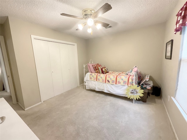 carpeted bedroom featuring a closet, ceiling fan, and a textured ceiling