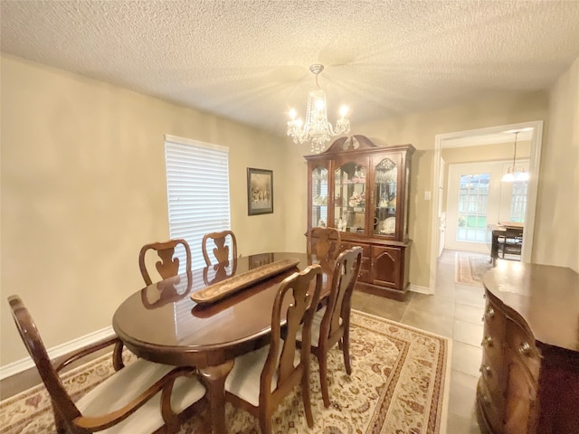 tiled dining area featuring a notable chandelier and a textured ceiling