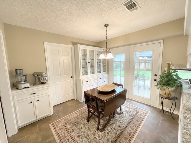 tiled dining space with an inviting chandelier and a textured ceiling