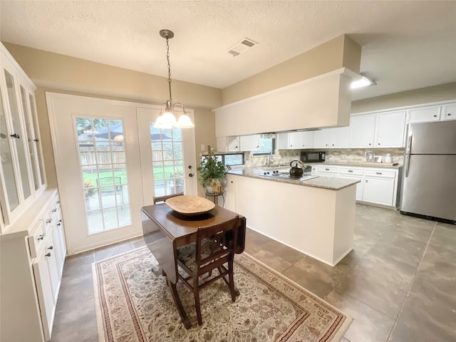 kitchen with appliances with stainless steel finishes, white cabinets, hanging light fixtures, and backsplash