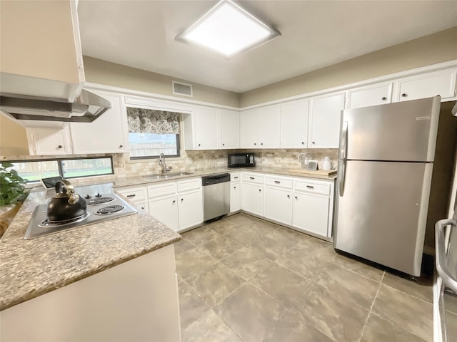 kitchen featuring backsplash, ventilation hood, sink, white cabinets, and appliances with stainless steel finishes