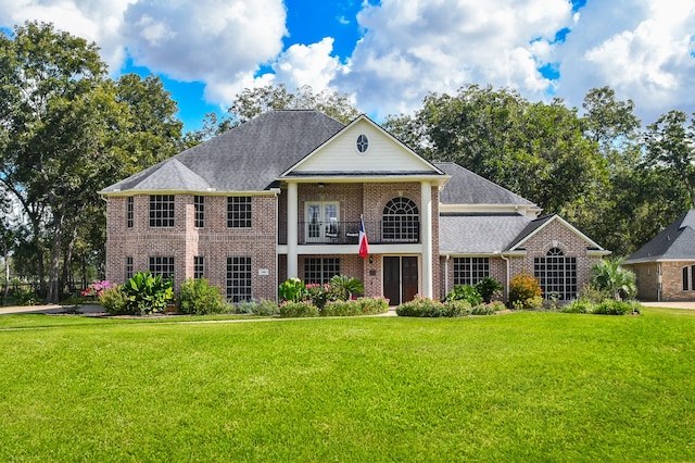 view of front of house with a balcony and a front lawn