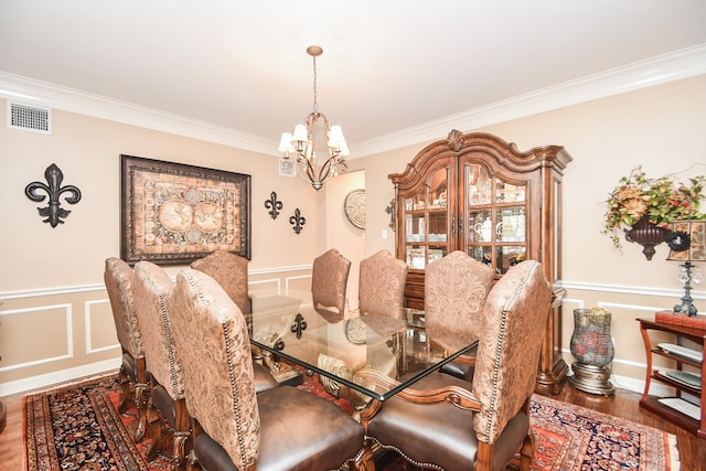 dining area with ornamental molding, a chandelier, and wood-type flooring