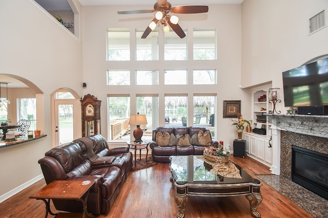 living room featuring a premium fireplace, a wealth of natural light, a high ceiling, and hardwood / wood-style floors