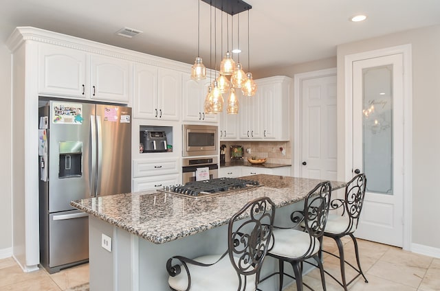 kitchen with dark stone countertops, appliances with stainless steel finishes, a center island, and white cabinets