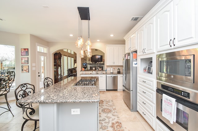 kitchen featuring light stone countertops, white cabinets, a kitchen bar, and stainless steel appliances