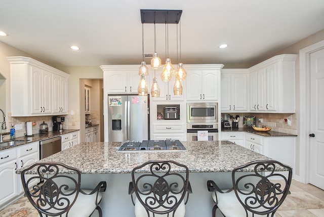 kitchen featuring stainless steel appliances, dark stone counters, a kitchen island, and white cabinets