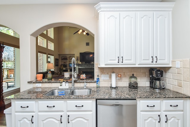 kitchen featuring sink, dishwasher, ceiling fan, dark stone counters, and white cabinets