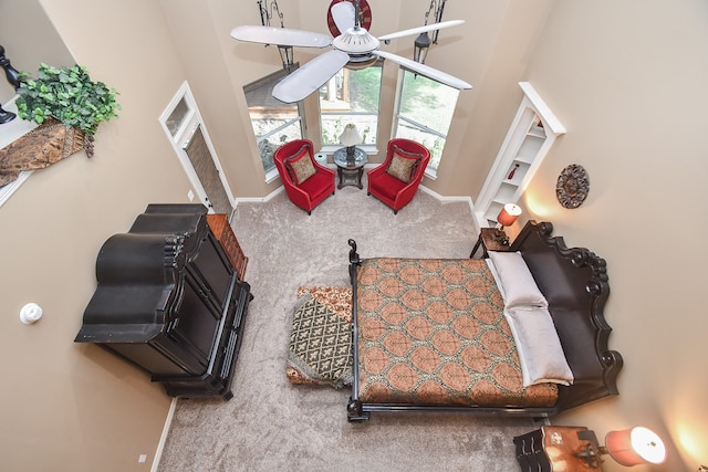 carpeted living room featuring a towering ceiling and ceiling fan