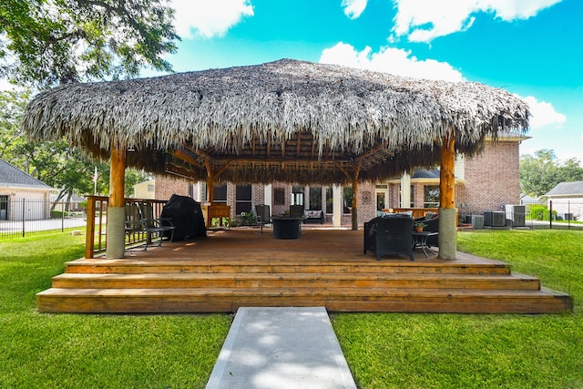 rear view of house with a yard, a gazebo, and a deck