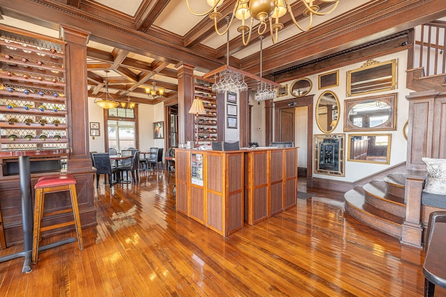 bar with hardwood / wood-style flooring, beamed ceiling, ornamental molding, decorative light fixtures, and an inviting chandelier