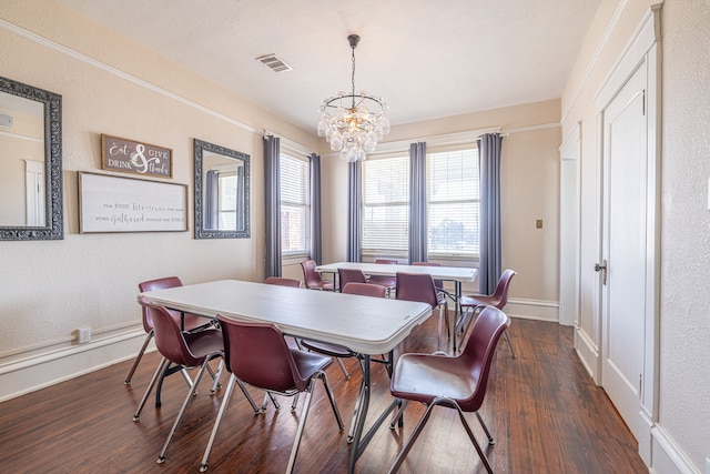 dining area with a wealth of natural light, a notable chandelier, and dark hardwood / wood-style floors