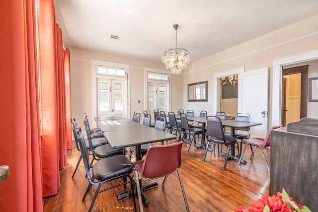 dining room featuring dark wood-type flooring, a notable chandelier, and french doors