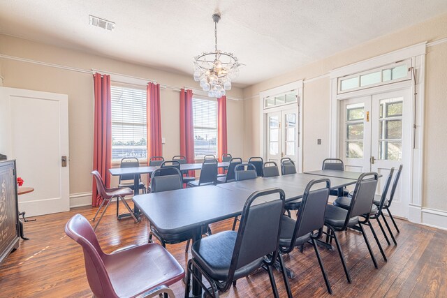 dining area with french doors, a textured ceiling, dark hardwood / wood-style flooring, and an inviting chandelier