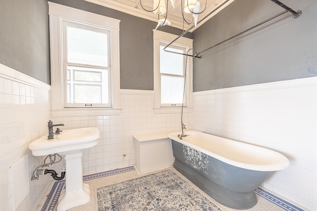 bathroom with tile walls, a chandelier, a washtub, and tile patterned flooring