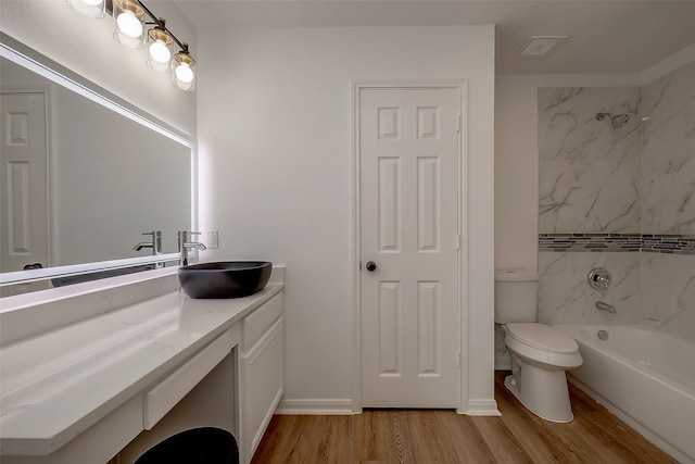 full bathroom with hardwood / wood-style flooring, vanity, toilet, and tiled shower / bath