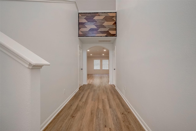 hall with a towering ceiling and light hardwood / wood-style flooring