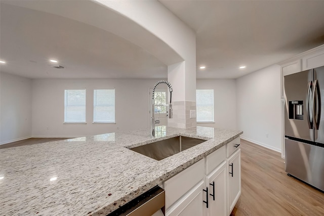 kitchen featuring sink, light hardwood / wood-style flooring, light stone countertops, white cabinetry, and stainless steel appliances