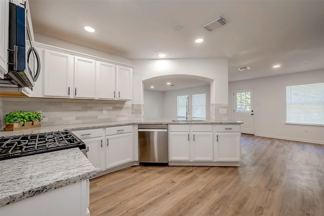 kitchen featuring decorative backsplash, appliances with stainless steel finishes, sink, light hardwood / wood-style flooring, and white cabinets