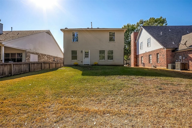 rear view of house featuring cooling unit, a lawn, and fence