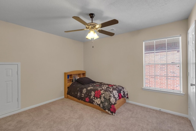 carpeted bedroom featuring ceiling fan and a textured ceiling