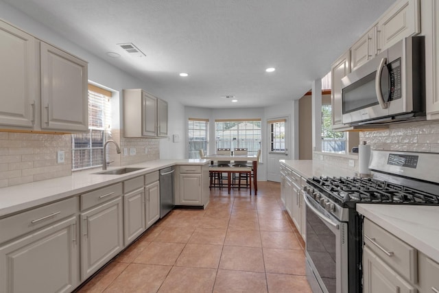 kitchen with decorative backsplash, light stone countertops, stainless steel appliances, sink, and light tile patterned flooring