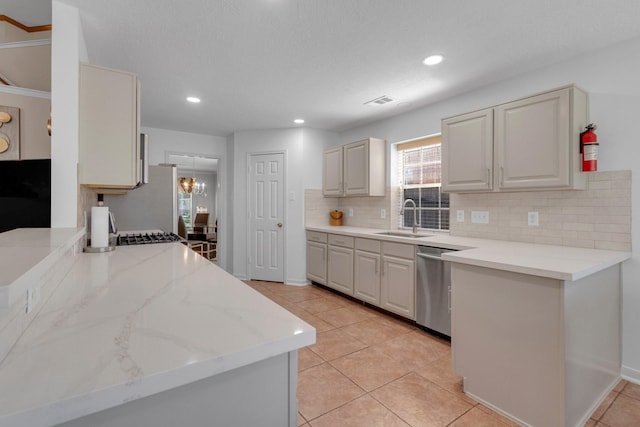 kitchen with sink, stainless steel dishwasher, decorative backsplash, light tile patterned flooring, and light stone counters