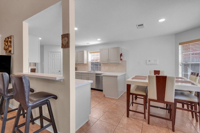 kitchen with dishwasher, sink, kitchen peninsula, a breakfast bar area, and decorative backsplash