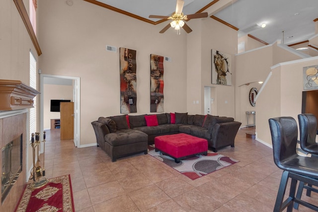 tiled living room with a fireplace, a high ceiling, ceiling fan, and beam ceiling