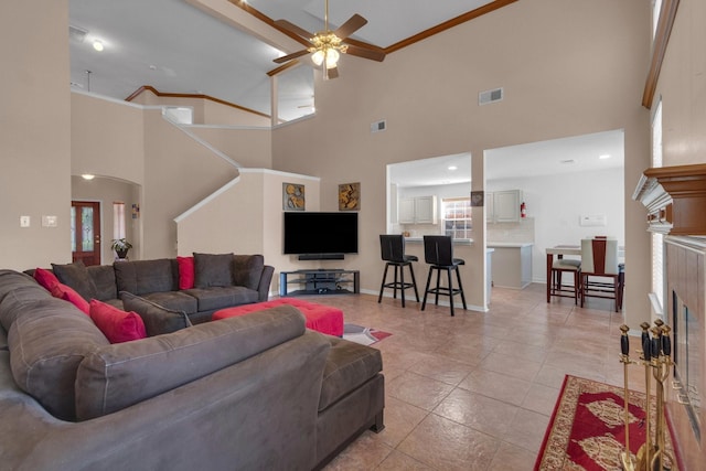 tiled living room with a high ceiling, ceiling fan, and crown molding