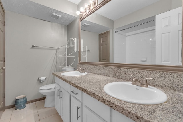 bathroom with tile patterned flooring, vanity, a textured ceiling, and toilet